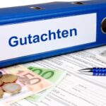 Ordner beschriftet mit 'Gutachten' neben Geld und Rechner