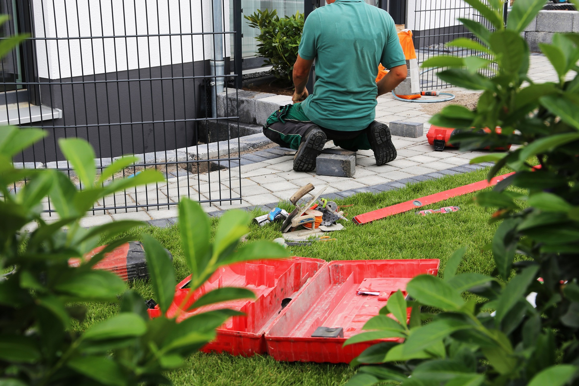 Gärtner kniet bei Pflasterarbeiten am Haus | Sonnensegel nach Maß